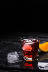 Mezcal Negroni cocktail. Italian aperitivo. Citrus peel. Ice.