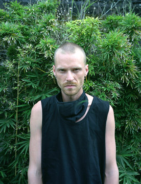 Portrait of young man standing against green trees