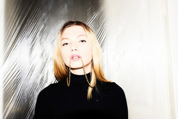 Beautiful blonde girl with gold chain in mouth.