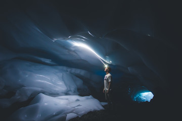 Young man looking toward the ceiling of an ice cave with his headlamp