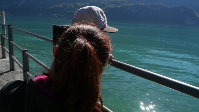 Mom and son, view around a woman and her kid, on a fence enjoying the view of a turquoise lake, on a sunny fall day, at brienzersee, in berner oberland, in the swiss alps of Switzerland