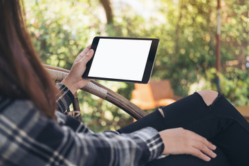 Mockup image of woman's hand holding black tablet pc with blank white screen while sitting outdoor...
