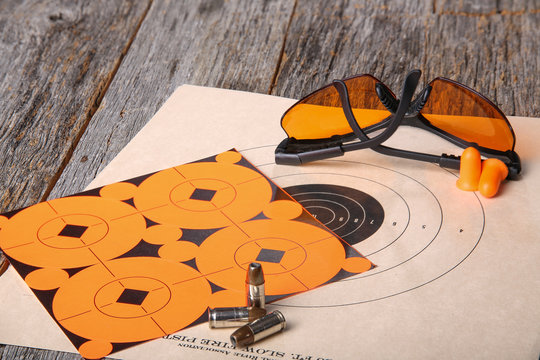 Semi automatic handgun at rest with eye protection and ear protection and paper practice targets and hollow point ammunition. 
