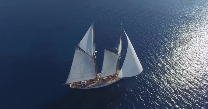 Flying above luxury racing yacht sailing on reflecting ocean waters