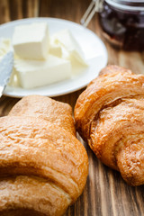 two croissants, butter and jam on the morning wooden table.