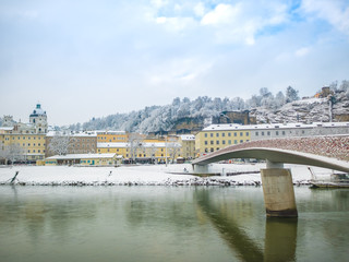 Naklejka premium landscape view of the famous historic city of Salzburg with Salzach river in beautiful bridge sky and clouds winter season snow Austria