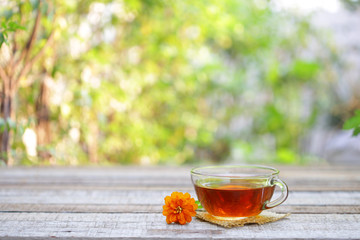 Red tea in clear glass and flower on wooden table
