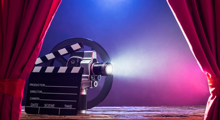 Movie Camera With Clapperboard And Film Reel On Stage - obrazy, fototapety, plakaty