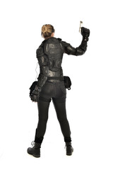 full length portrait of female  soldier wearing black  tactical armour, holding a gun, isolated on white studio background.