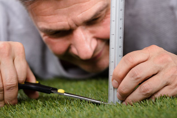 Man Using Measuring Scale While Cutting Grass