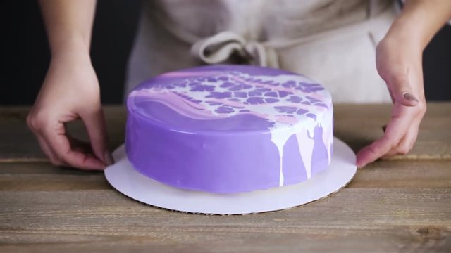 Step by step. Pastre shef decorating mousse cake with purple mirror glaze with chocolate pink flowers