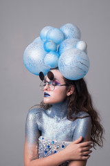Naklejka premium Young attractive girl in makeup, in glasses and balloons on the head