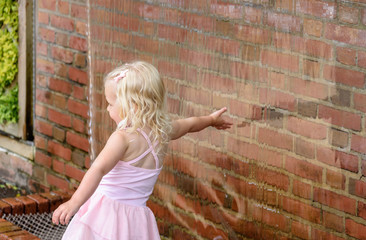 little girl reaching her hand into waterfall wall touching water