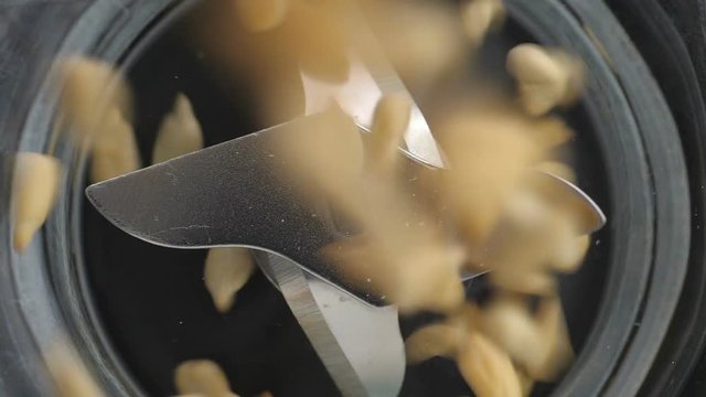 Falling grains of sunflower seeds in sharp blender blades. High angle view.
