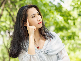 Beautiful young brunette Asian woman thinking with her index finger on her head. Outdoor fashion portrait of glamour young Chinese stylish lady. Emotions, people, beauty and lifestyle concept.