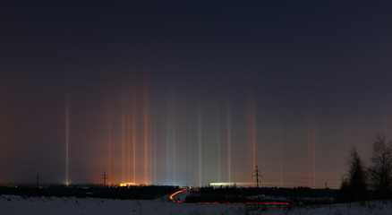 Fototapeta na wymiar Multicolored radiance in the atmosphere. Natural phenomenon in the night sky over the highway.