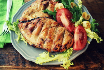 Grilled chicken breast with tomatoes, endive on a wooden table. Top view