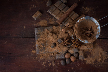 Chocolate, Spices, Spoon with Cocoa, Metal Strainer, Hazelnut on Dark Wooden Background. Copy space. Flat lay, top view
