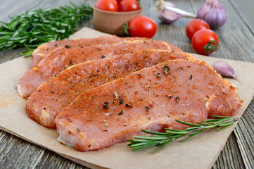 Fresh and raw meat. Sirloin steaks in a row ready to cook. Large pieces of raw meat in marinade with spices on paper on a wooden table.