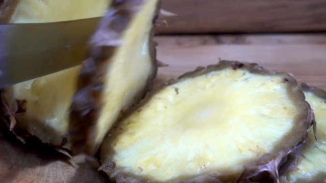 Cutting pineapple into slices with a knife on a wooden board. HD video clip