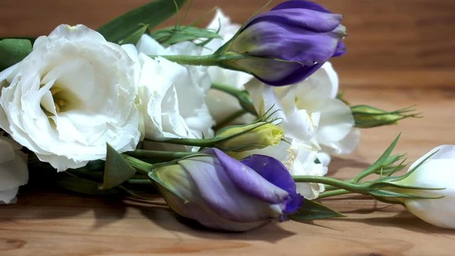 Close-up of a bouquet of tender white and purple flowers on a wooden background. HD video clip
