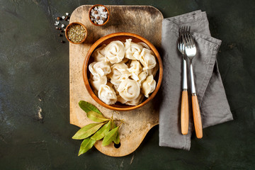 Traditional russian pelmeni, ravioli, dumplings with meat on concrete background.  Russian food and russian kitchen concept. Top view.