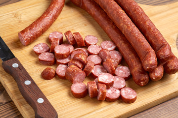 Thin smoked sausage whole and sliced on a wooden background. Close-up.