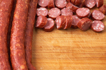 Thin smoked sausage whole and sliced on a wooden background. Close-up.