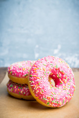 Donut with sprinkles on the rustic wooden background. Selective focus.