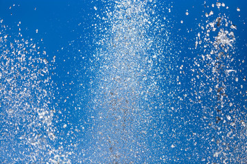 Splashing water from a fountain against the blue sky