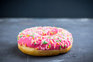 Donut with sprinkles on the rustic wooden background. Selective focus.