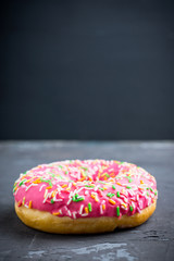 Donut with sprinkles on the rustic wooden background. Selective focus.