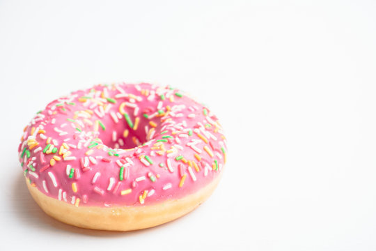 Donut with sprinkles on the rustic wooden background. Selective focus.