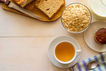 Fototapeta na wymiar Healthy breakfast. Oatmeal, tea and fresh pastries - copy space, top view. Natural lighting