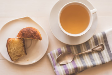 cup of green tea, fresh cake and a napkin on a light table - rustic breakfast