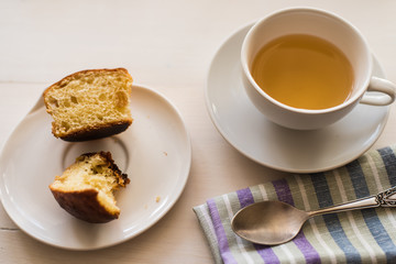 cup of green tea, fresh cake and a napkin on a light table - rustic breakfast