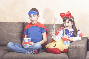 Happy kids dressed up as super heroes and fantasy characters watching TV