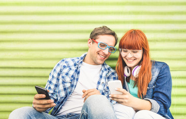Happy young couple having fun with mobile smart phone at vintage grunge location - Friendship...
