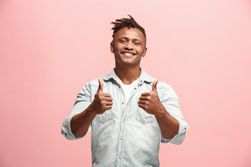 The happy business man standing and smiling against pink background.