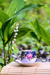 Beautiful fairy picture with a cup of tea and lilies of the valley