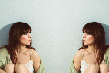 Sitting woman looking at her doppelgänger