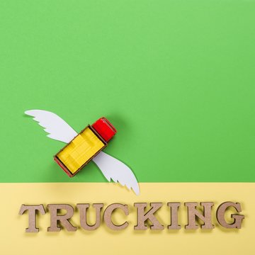 Abstract picture of a truck with wings and a word of trucking. Cargo transportation of the future.