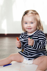 portrait of a baby drawing on the floor in a room on a sunny day