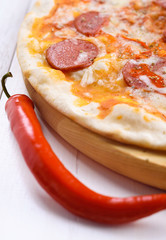 Close up of hot homemade pepperoni pizza on wooden board ready to eat. Fresh pizza with pepperoni, mozzarella and tomato sauce. Italian traditional cuisine. Italian food, shallow depth of field