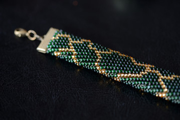 Dark green beaded necklace with golden print on a dark background close up