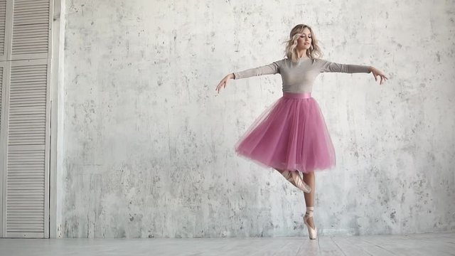 an elegant young ballerina is dancing a classical ballet on the background of a huge light window. ballet dancer in a classic tutu and pointe