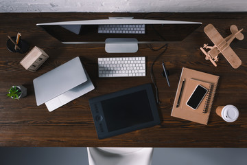 top view of graphics tablet, laptop, smartphone and desktop computer at workplace