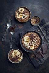morning chocolate oat porridge with fresh bananas on black background