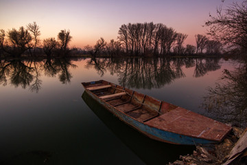 Vibrant wide angle landscape panorama with lonely boat in sunset in fall