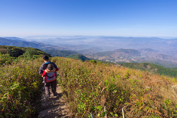 Obraz premium Doi Inthanon National Park, The hill tribe carrying a child walk on the top highest mountain of Thailand